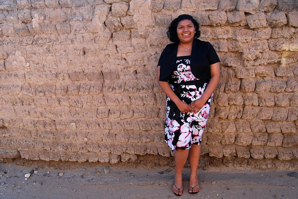 girl posing in front of an adobe wall