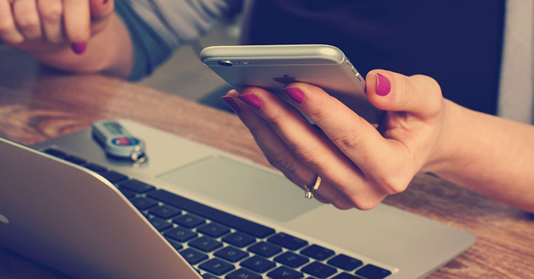Woman holding an iPhone while working from home